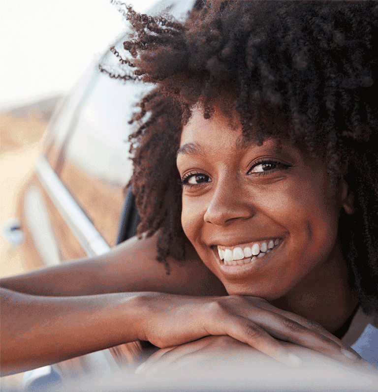 Smiling woman enjoying her car, looking out of the window with a sense of satisfaction and contentment.